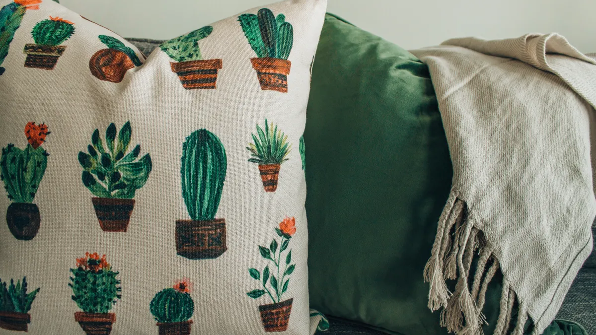 Cactus-print pillow cover beside a green cushion